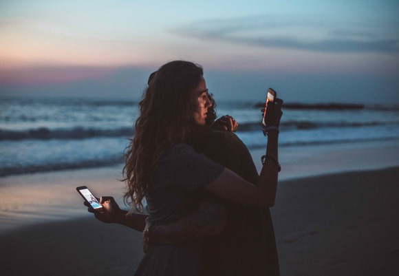 Couple hugging and using smartphone near sea on sunset 4555321 kopie